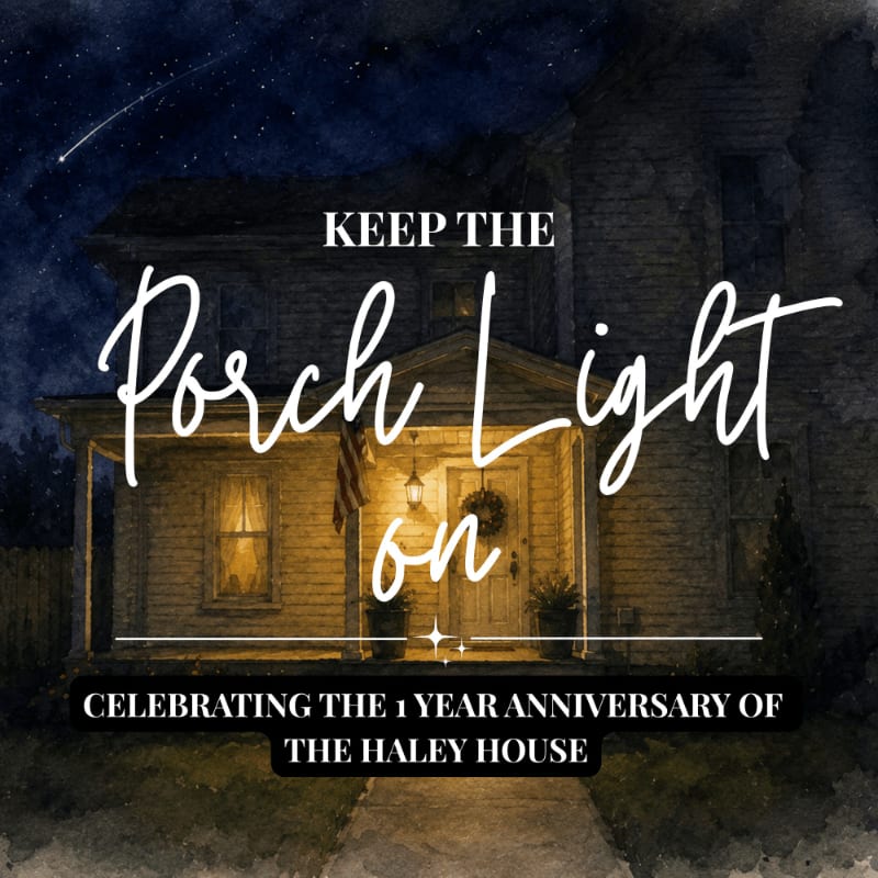 A warmly lit house with a porch light on stands against a dark, starry night sky with a shooting star.