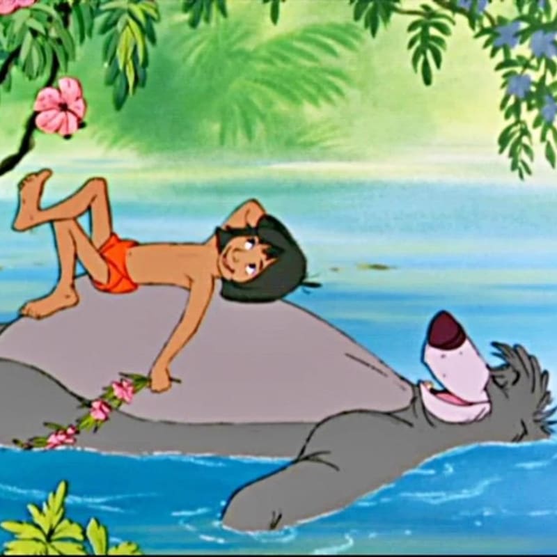 Mowgli relaxes on Baloo's back in the water, with lush green foliage and pink flowers in the background.
