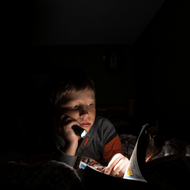 boy in black and white long sleeve shirt holding book