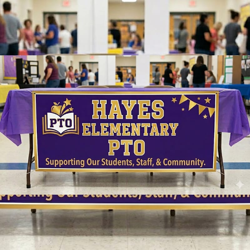 A purple tablecloth with a "Hayes Elementary PTO" banner is set up in the foreground, while a blurred background shows people milling about in a school hallway.