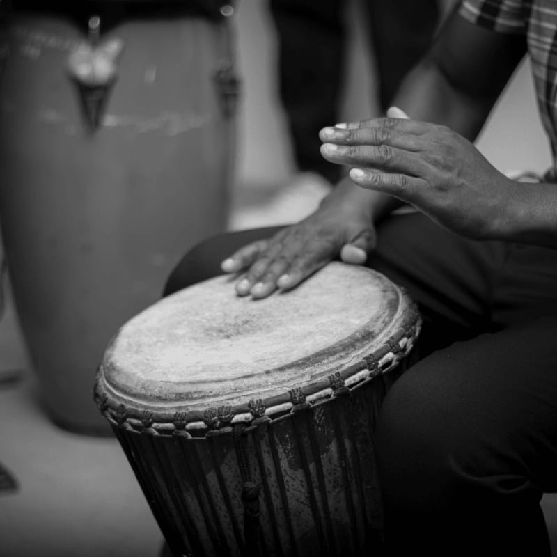 A person playing a djembe drum with hands
