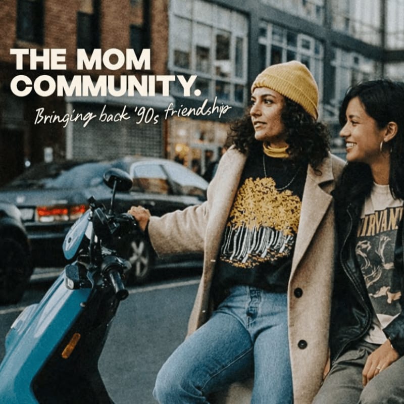 Two women in casual 90s-inspired clothing sit on a scooter in the foreground, with a blurred urban street scene and buildings in the background.