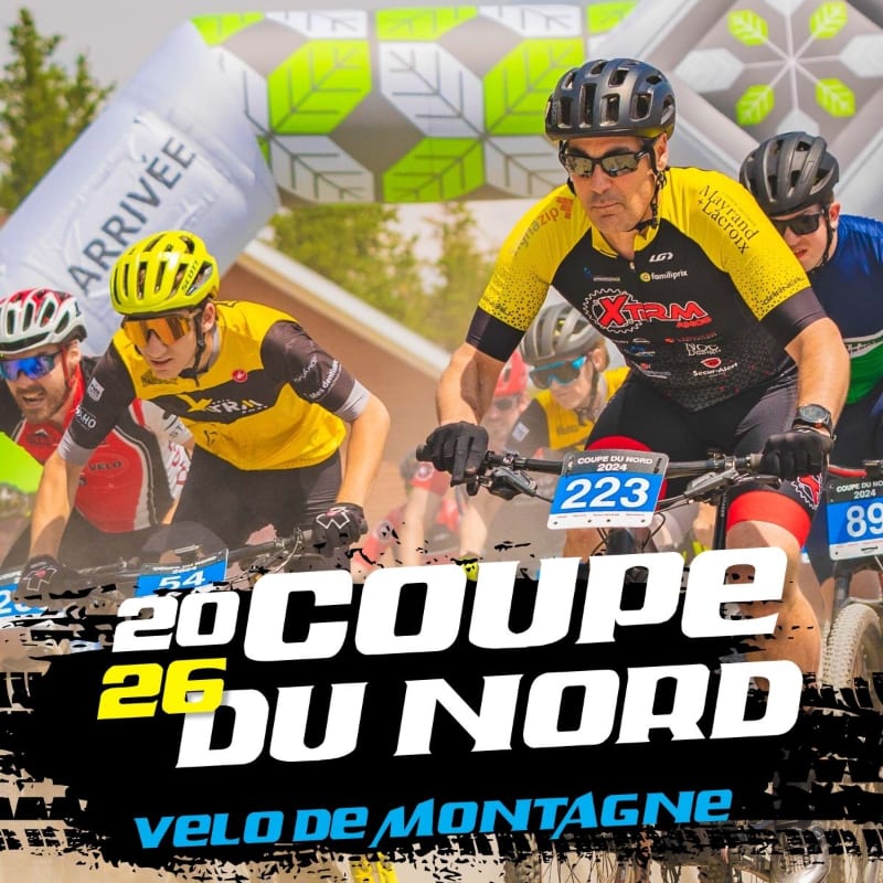 Cyclists in bright jerseys race towards an "ARRIVÉE" archway in the foreground, with a blurred background of trees and buildings.