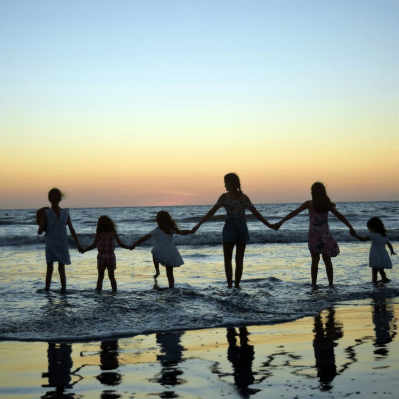 a family holding hands on the beach at sunset