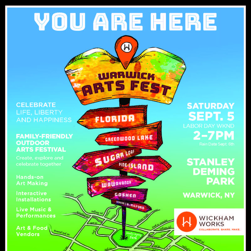 A colorful signpost for the Warwick Arts Fest stands in the foreground against a bright blue sky, with event details and a map of the area in the background.