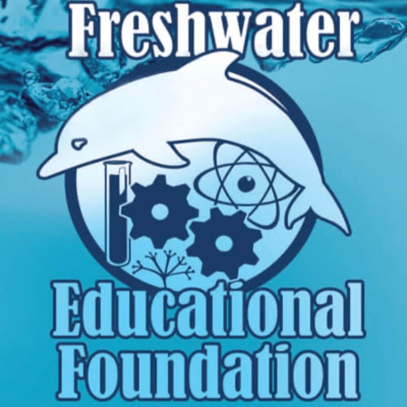 A white dolphin leaps over a circular emblem containing scientific imagery, set against a blue, watery background with splashes of water in the foreground.