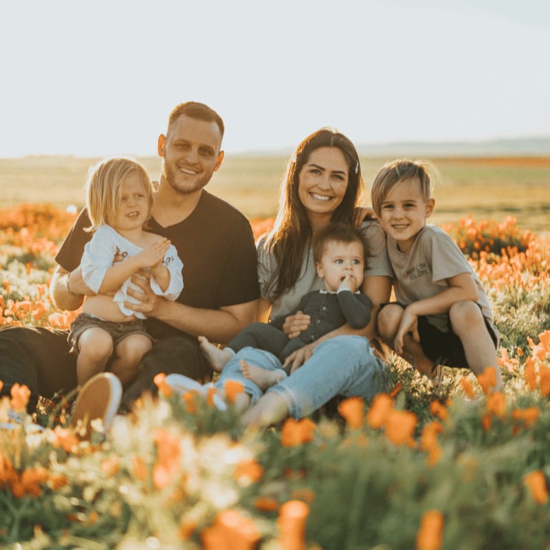 3 women and 2 men sitting on green grass field during daytime