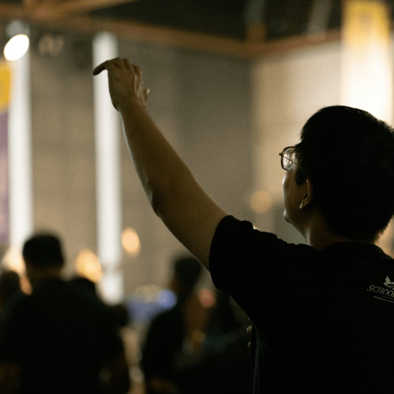 Person raising hand in a crowded room