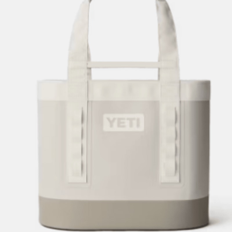 A light-colored YETI tote bag with beige handles stands against a plain gray background.