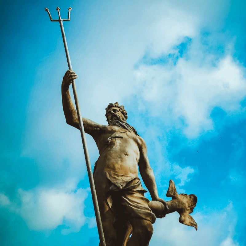 man holding trident statue under white clouds at daytime