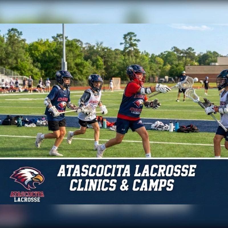Young boys in lacrosse gear run on a green field in the foreground, while a blurred background shows spectators and trees under a bright sky.