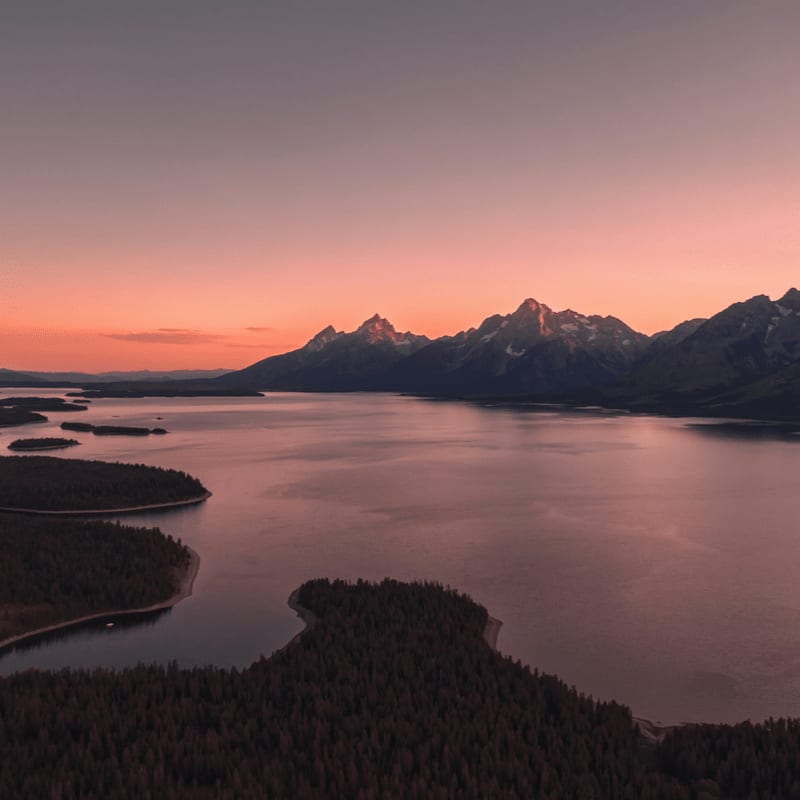body of water near mountain during sunset