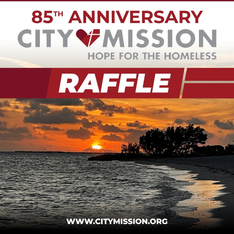A serene beach sunset with gentle waves lapping the shore forms the background for a "RAFFLE" announcement for the 85th Anniversary City Mission.