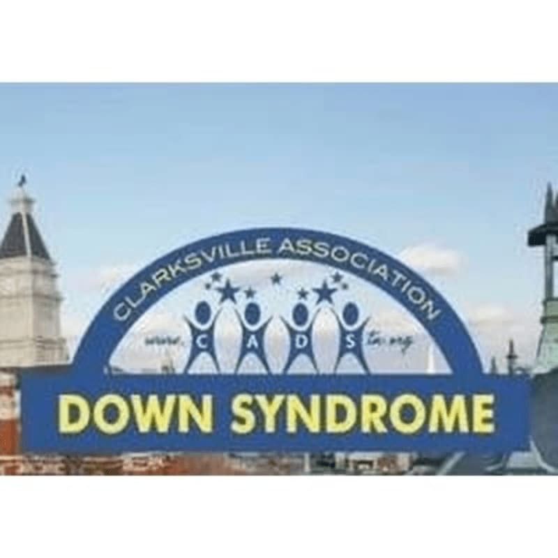 A blue archway with "CLARKSVILLE ASSOCIATION" and "DOWN SYNDROME" in yellow lettering stands in the foreground against a backdrop of buildings and a clear sky.