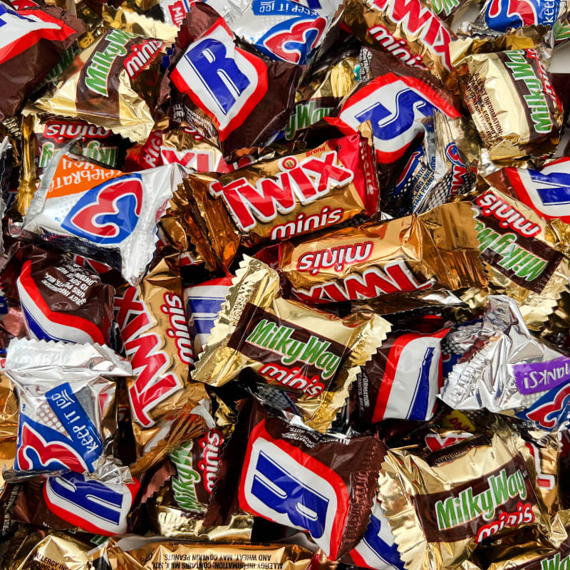 A pile of miniature candy bars, including Snickers, Twix, and Milky Way, fills the frame.