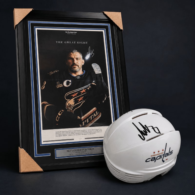 A framed portrait of a hockey player stands next to a signed white hockey helmet with the Washington Capitals logo.