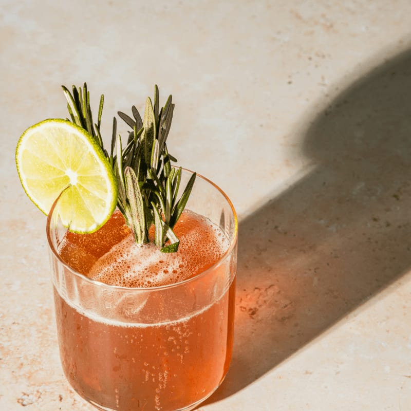 cocktail with lime and rosemary garnish
