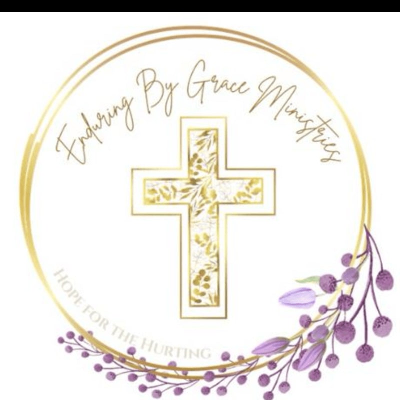 A golden cross with floral accents is centered within a circular emblem that reads "Enduring By Grace Ministries" and "Hope for the Hurting," framed by delicate purple flowers and leaves.