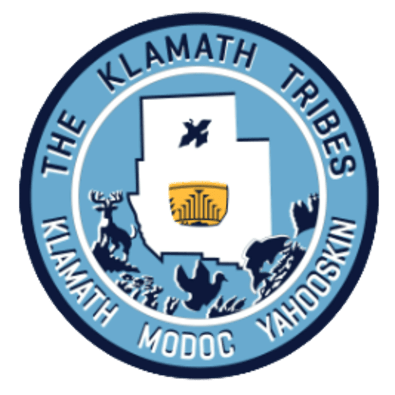 A circular emblem features a white silhouette of Oregon with tribal symbols and animals in the foreground against a light blue background.