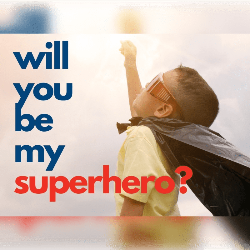A young boy in a superhero cape and goggles reaches towards the sky in front of a bright, cloudy background with the words "will you be my superhero?" superimposed on the left.