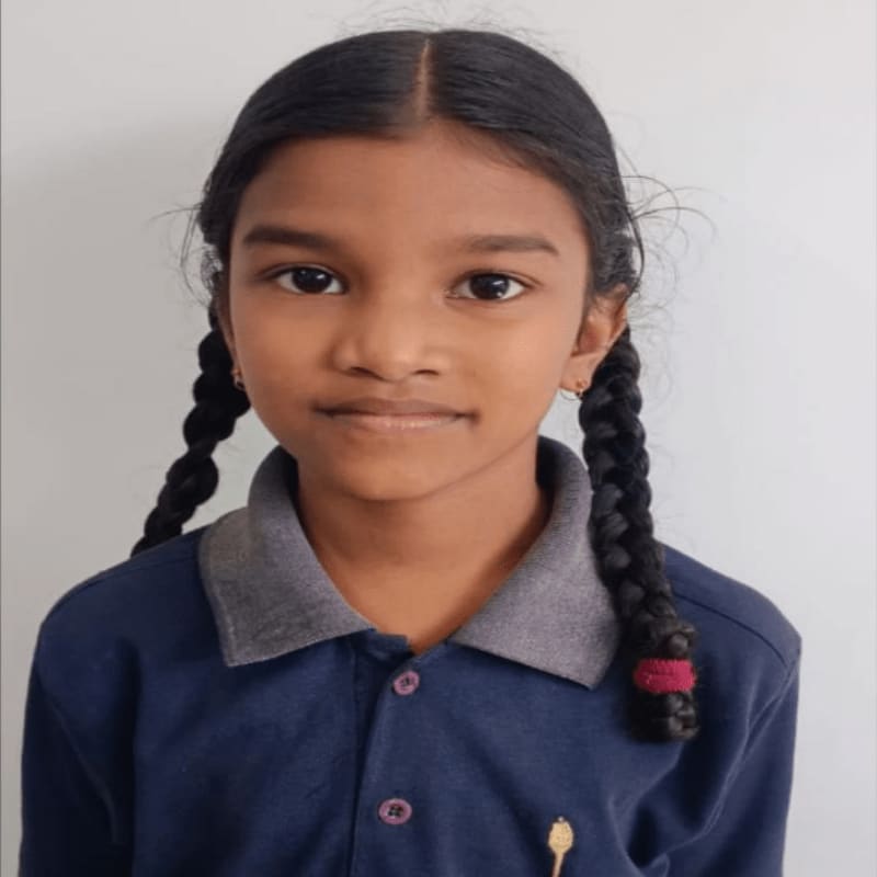 A young girl with braided hair and a navy blue collared shirt smiles against a plain white background.