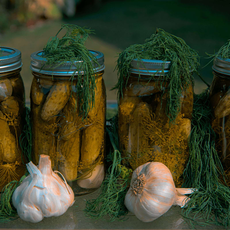 white garlic and green vegetable in clear glass jar