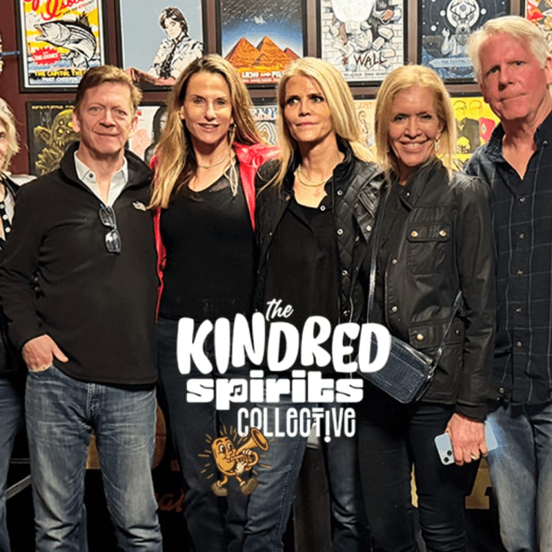 A group of five people stand in front of a wall adorned with colorful posters.