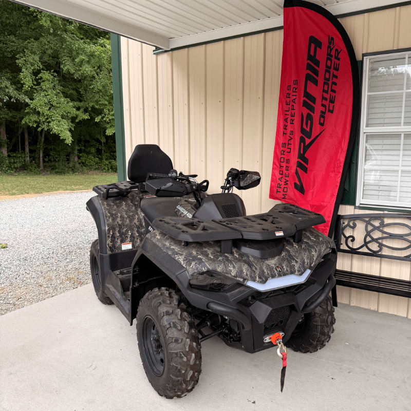 A camouflage ATV sits in the foreground on a concrete pad, with a red "Virginia Outdoors Center" banner and a building in the background.