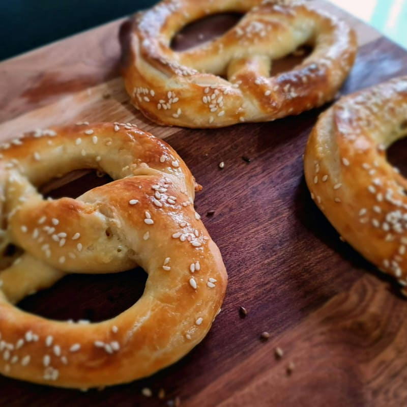 a wooden cutting board topped with three pretzels