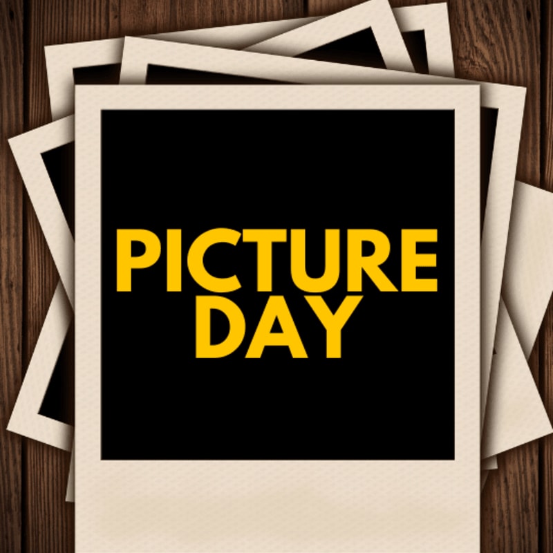 A stack of instant photos with "PICTURE DAY" in yellow text on a black background rests on a rustic wooden surface.