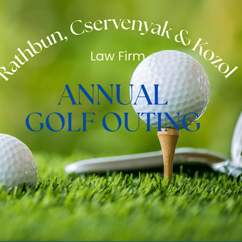 A golf ball sits on a tee in the foreground, with a blurred green background and text announcing an "Annual Golf Outing" for Rathbun, Cservenyak & Kozol Law Firm.
