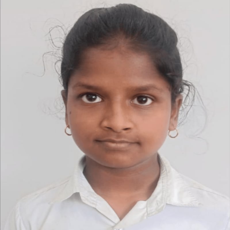 A young girl with dark hair and brown eyes, wearing a white collared shirt, is centered against a plain, light gray background.