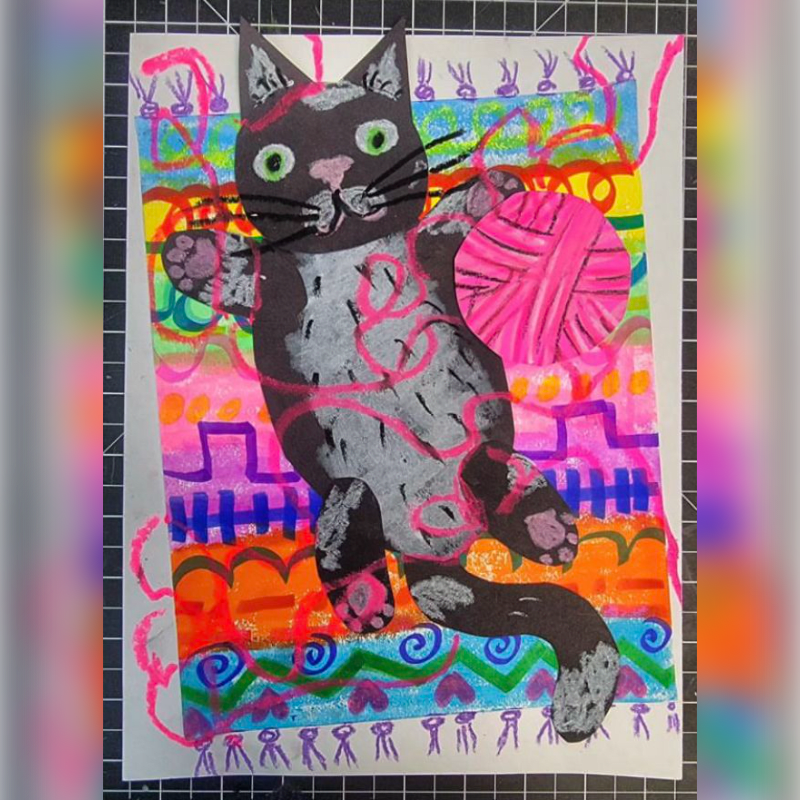 A playful black and white cat with green eyes holds a pink ball of yarn against a vibrant, colorful background of abstract patterns.
