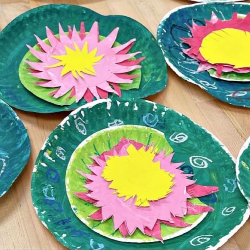 Colorful paper plate water lilies with pink and yellow petals rest on a wooden surface.