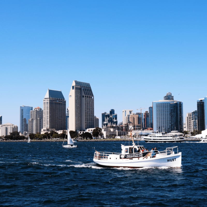 Boats cruise in front of a city skyline.