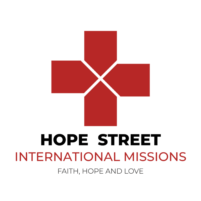 A red cross symbol with white accents is centered above the bold black text "HOPE STREET" and the red text "INTERNATIONAL MISSIONS," with "FAITH, HOPE AND LOVE" in smaller gray text below, all on a white background.