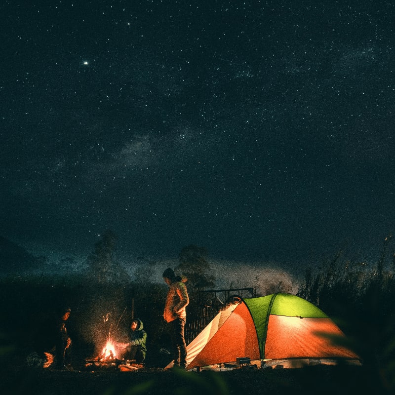 man in green and yellow tent under starry night