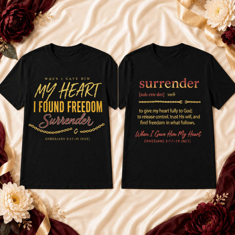 Two black t-shirts with Christian messages about surrender and freedom are laid out on a textured cream fabric, framed by burgundy and gold floral arrangements and draped fabric.