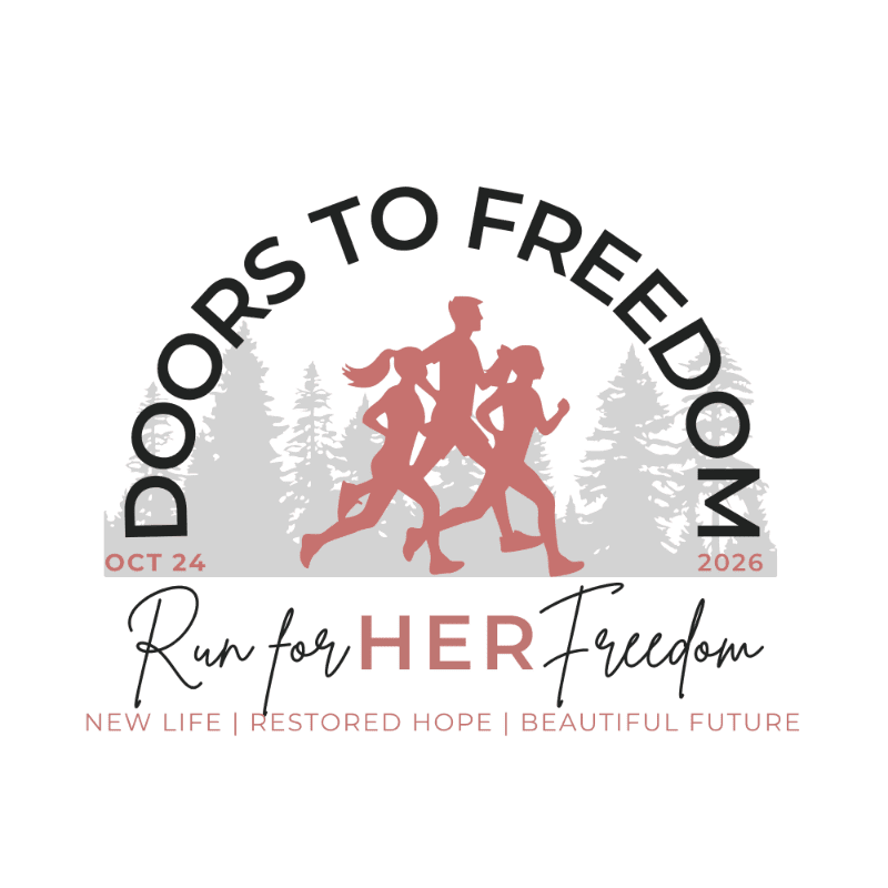 Silhouettes of three runners are in the foreground against a backdrop of trees, with the text "DOORS TO FREEDOM" arching above and "Run for HER Freedom" below.