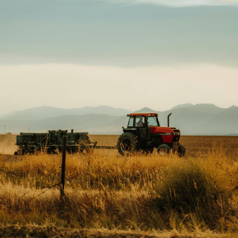 a tractor and trailer in a field with mountains in the background
