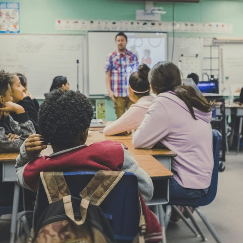 students in classroom with teacher presenting