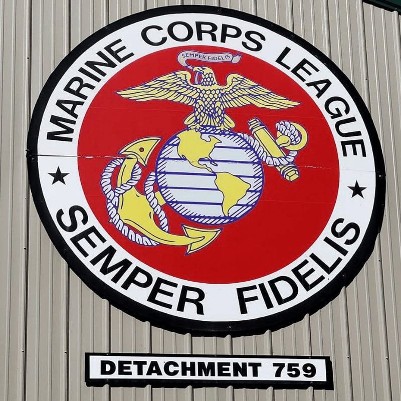 A circular Marine Corps League emblem with "SEMPER FIDELIS" and "DETACHMENT 759" is mounted on a corrugated metal wall.