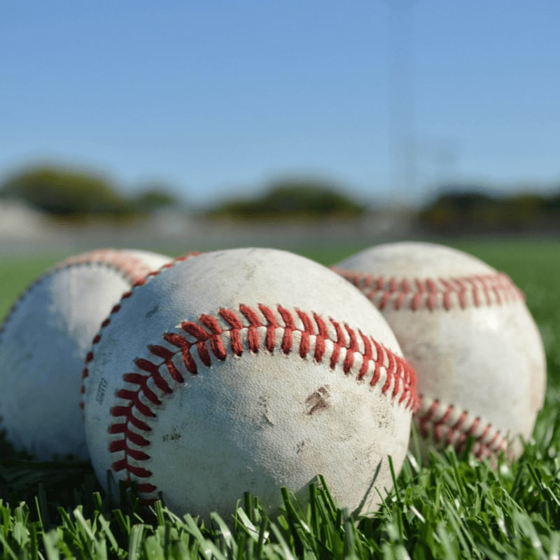 white and red baseball on green grass during daytime