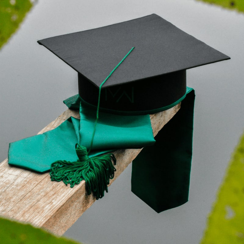 a graduation cap and a green tassel on a piece of wood