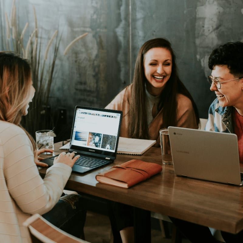 three people sitting in front of table laughing together