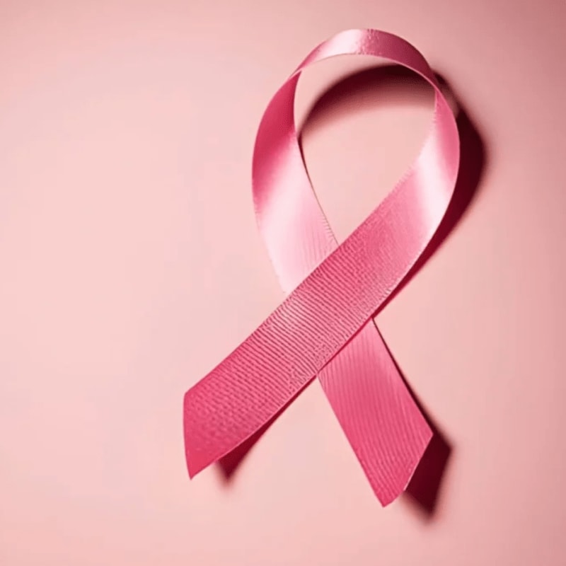 A pink ribbon lies on a soft pink background.