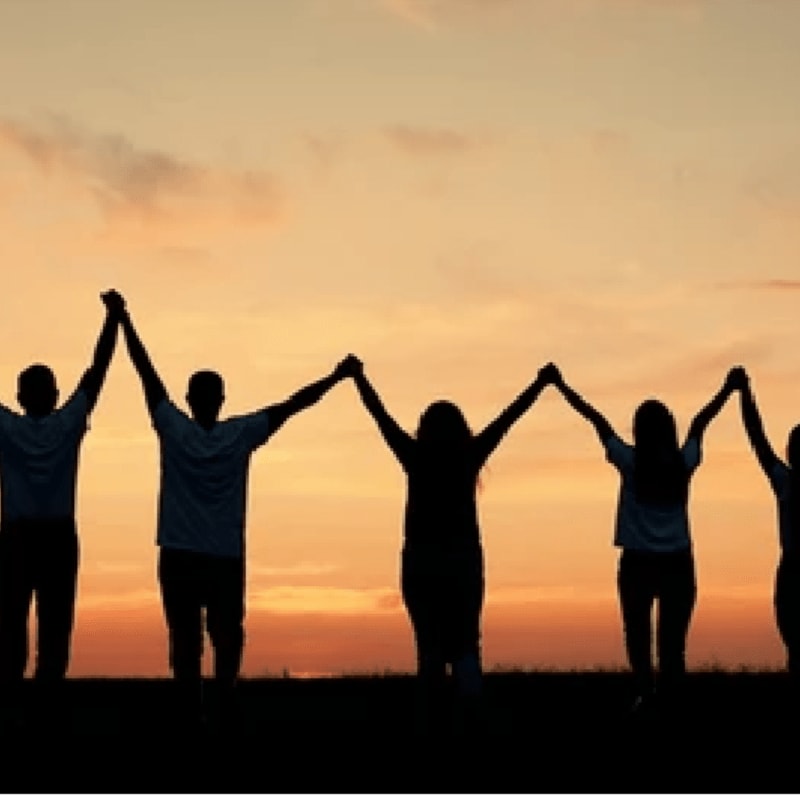 Silhouetted figures hold hands against a vibrant sunset sky.