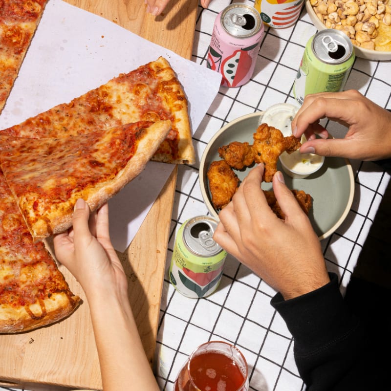 person holding sliced pizza on white ceramic plate