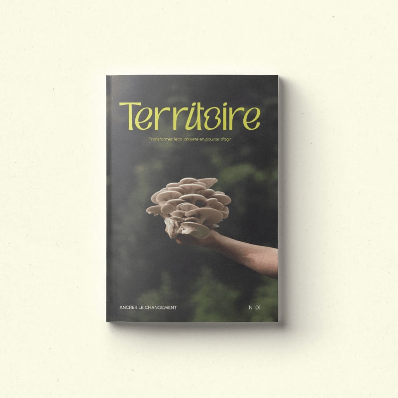 A magazine cover titled "Territoire" features a hand holding a cluster of mushrooms in the foreground against a blurred green background.