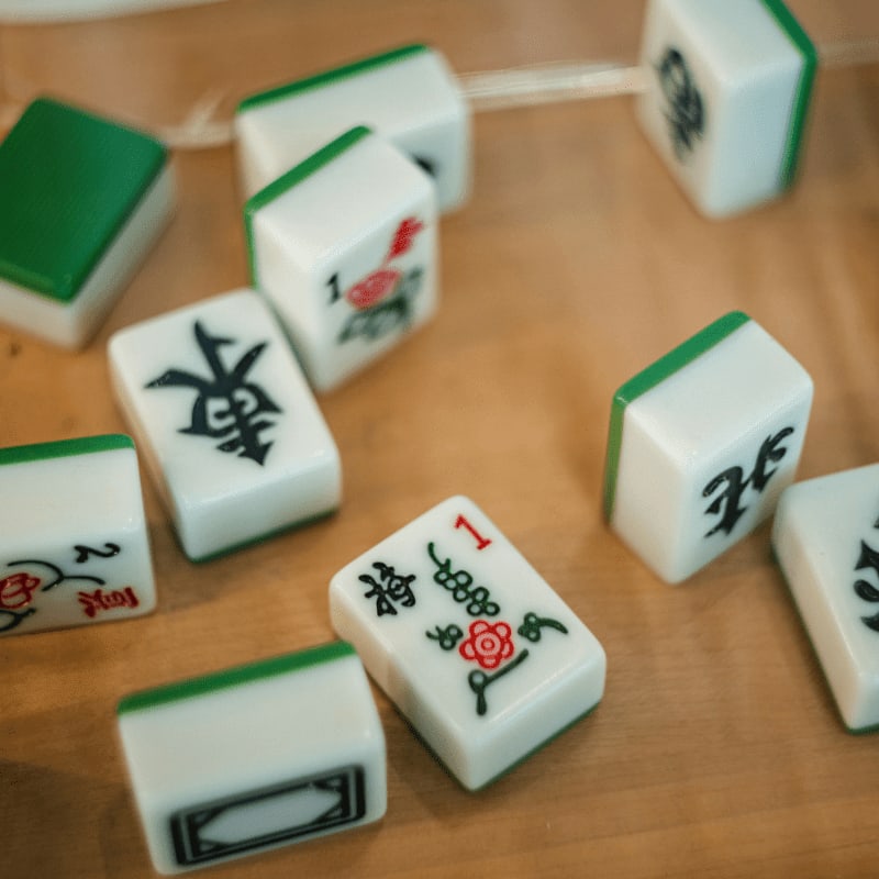 Mahjong tiles scattered on a wooden table.